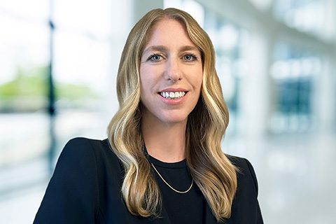 Blonde woman in a black top smiles in a blurred lobby