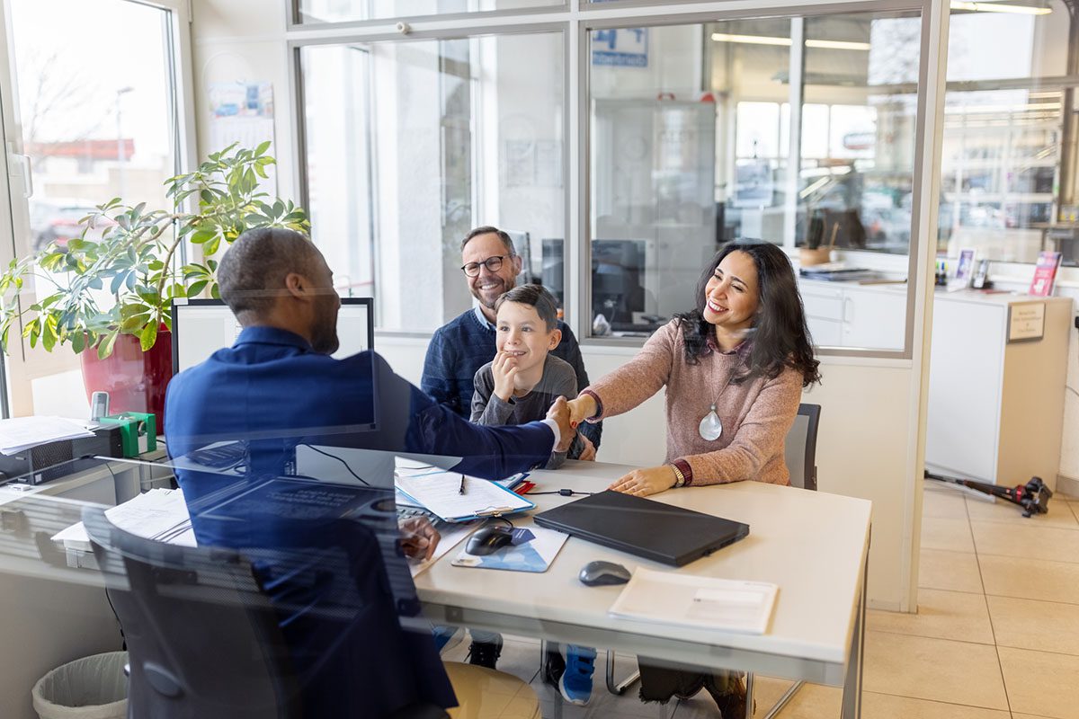Car salesman shaking hands with family
