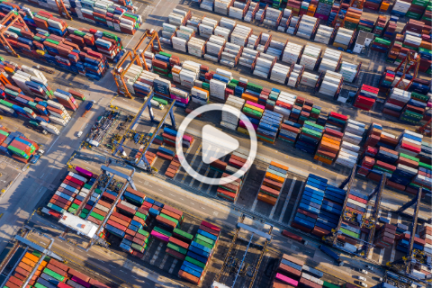 Aerial view of a large shipping container yard with rows of multicolored containers and cranes arranged in an organized layout.