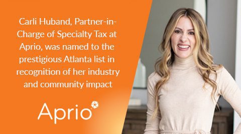 Carli Huband stands smiling next to a wall; text highlights her recognition on an Atlanta list for industry and community impact as Partner-in-Charge of Specialty Tax at Aprio.