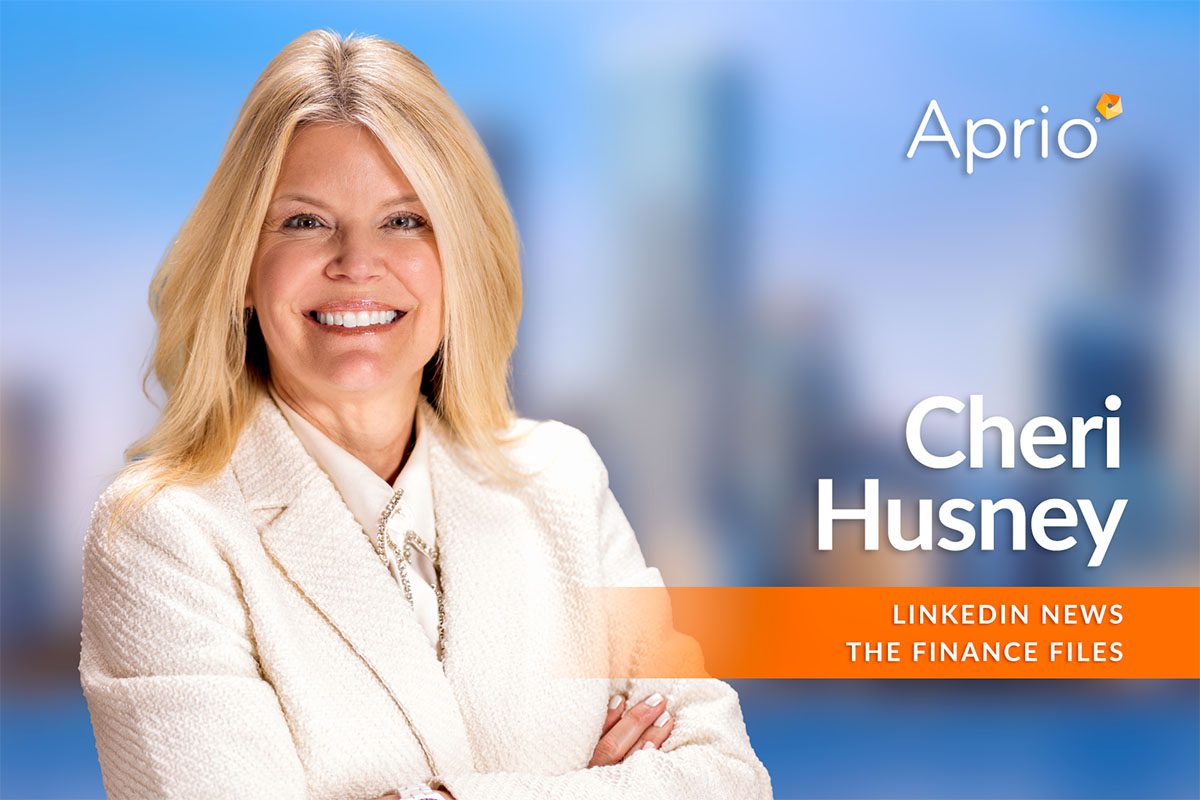 A woman in a white suit smiles with arms crossed in front of a blurred cityscape background. Text reads: “Aprio, Cheri Husney, LinkedIn News, The Finance Files.”.