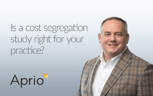 Smiling man in a plaid suit stands next to text that reads, Is a cost segregation study right for your practice? with the Aprio logo underneath.