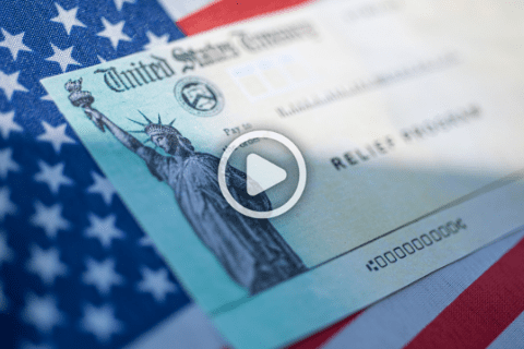 A U.S. Treasury relief check rests on an American flag, with a play button icon overlayed in the center of the image.