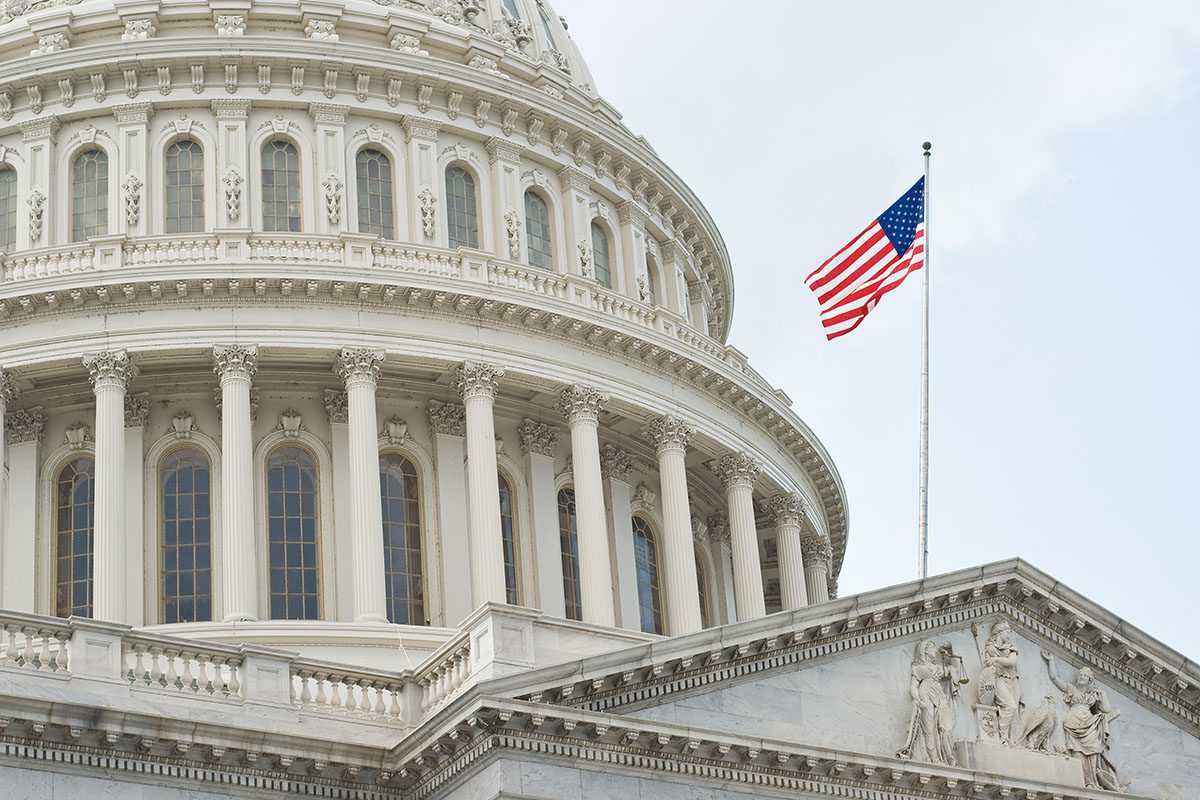 Close-up view of the United States Capitol building dome with the American flag flying on a flagpole in front.