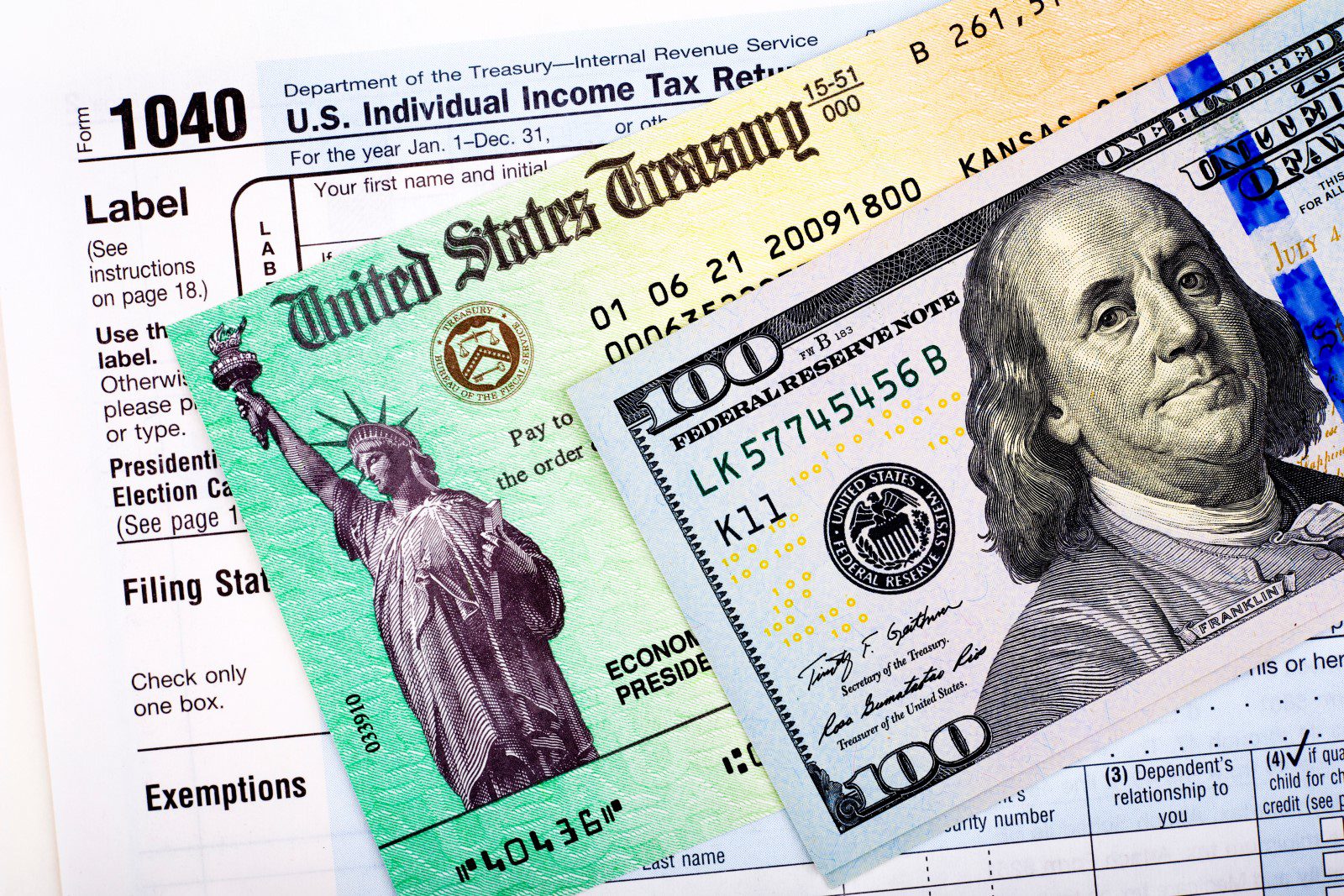 A U.S. Treasury check, a $100 bill, and a Form 1040 tax document are shown arranged together, representing tax refunds and income tax filing in the United States.