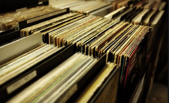 Rows of vinyl records are organized upright in crates, with colorful album covers visible along the spines.