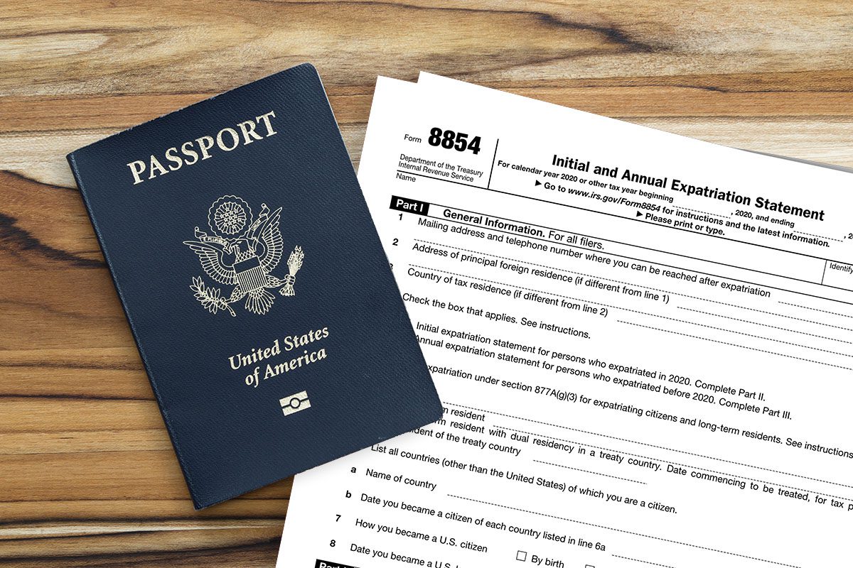 A U.S. passport and IRS Form 8854 titled Initial and Annual Expatriation Statement are placed side by side on a wooden surface.