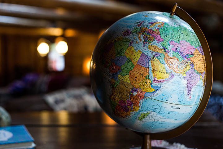 A colorful globe sits on a wooden table in a dimly lit room, displaying countries in Africa, Europe, and Asia.