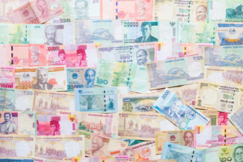 Assorted colorful banknotes from various countries are spread out in an overlapping pattern.