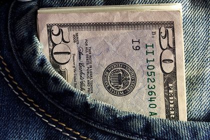 A fifty-dollar bill sticking out of the front pocket of blue denim jeans.