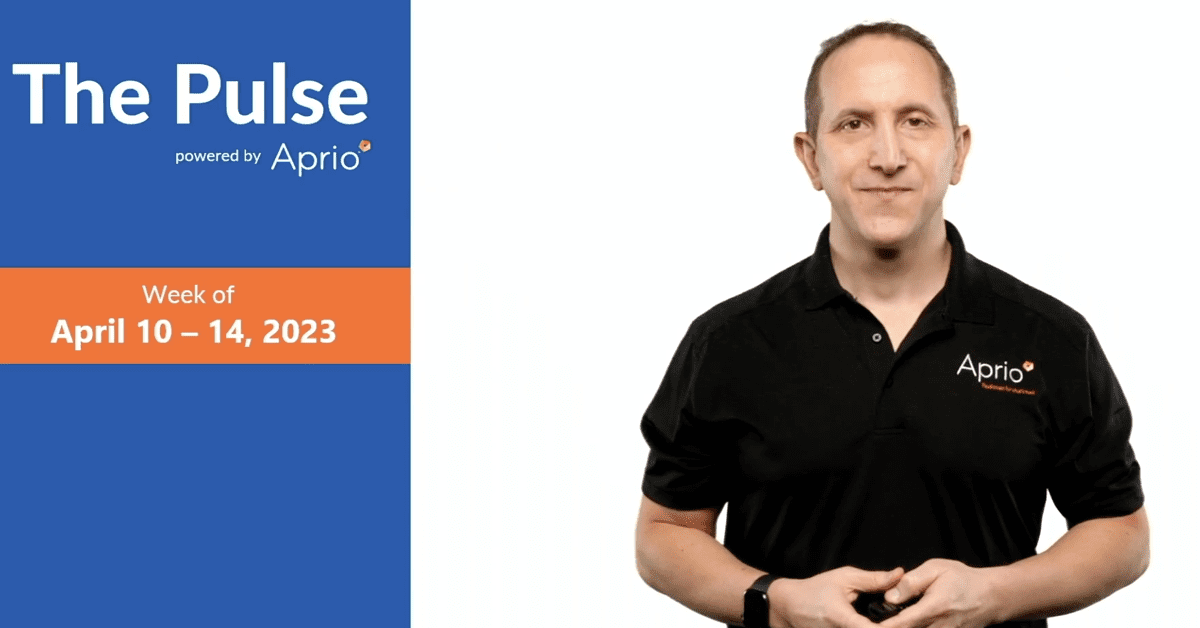 A man in a black Aprio shirt stands next to a display reading “The Pulse powered by Aprio, Week of April 10–14, 2023” on a blue and orange background.