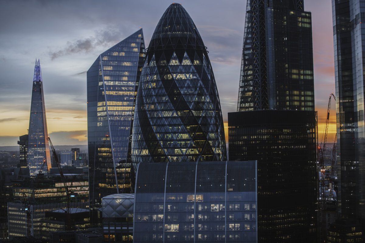 Several modern skyscrapers, including the Gherkin and the Shard, stand in London’s financial district at sunset.