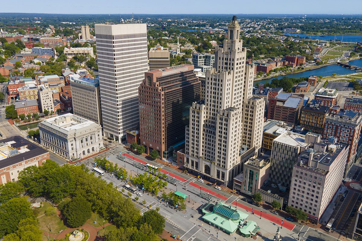 Aerial view of downtown Providence, Rhode Island, featuring tall office buildings, streets, and a nearby river under a clear sky.