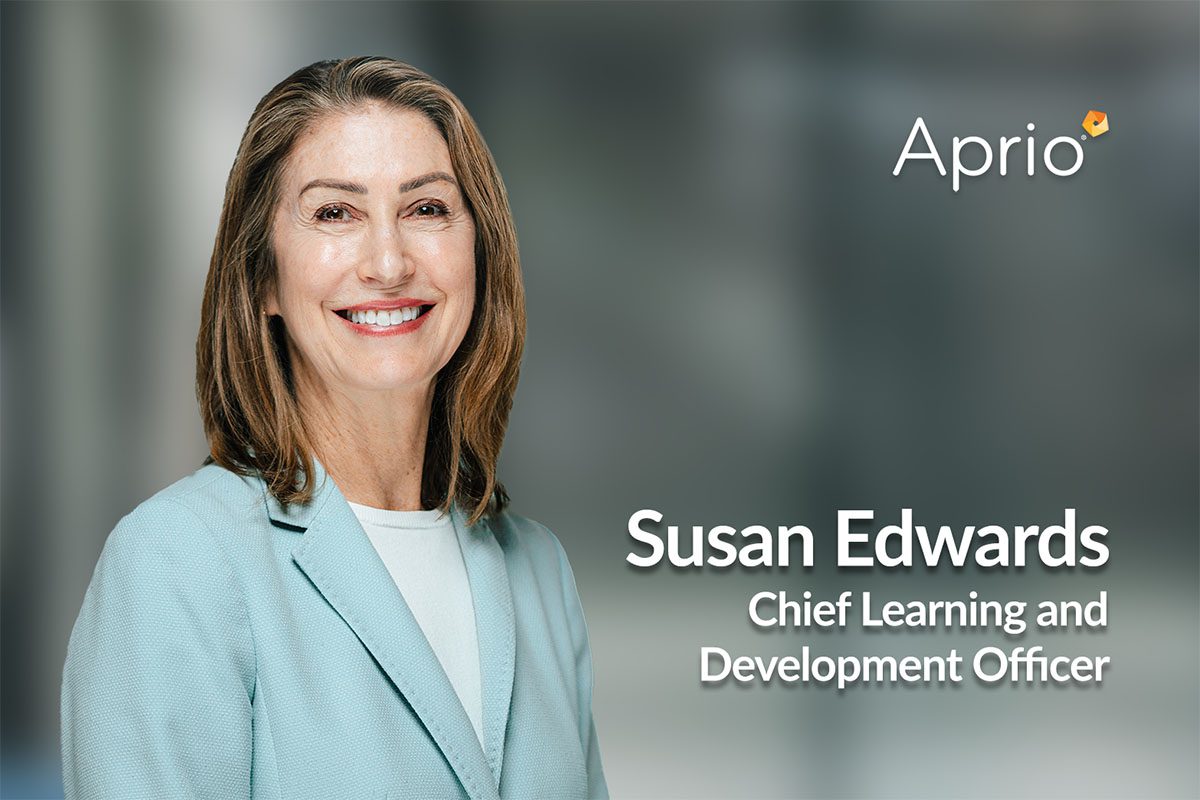 A woman in a light blue blazer smiles at the camera. Text reads: Susan Edwards, Chief Learning and Development Officer, Aprio on a blurred background.