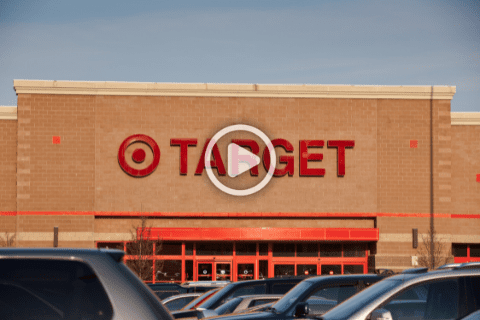 The front entrance of a Target store with the red Target logo and several cars parked in the foreground.