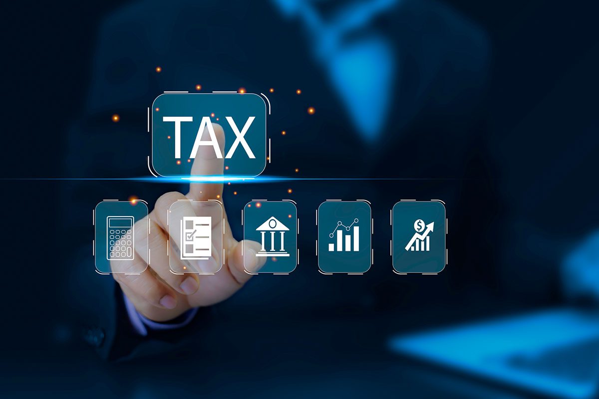 A person in a business suit touches a virtual screen displaying the word TAX and financial icons, including a calculator, documents, bank, charts, and a dollar sign.