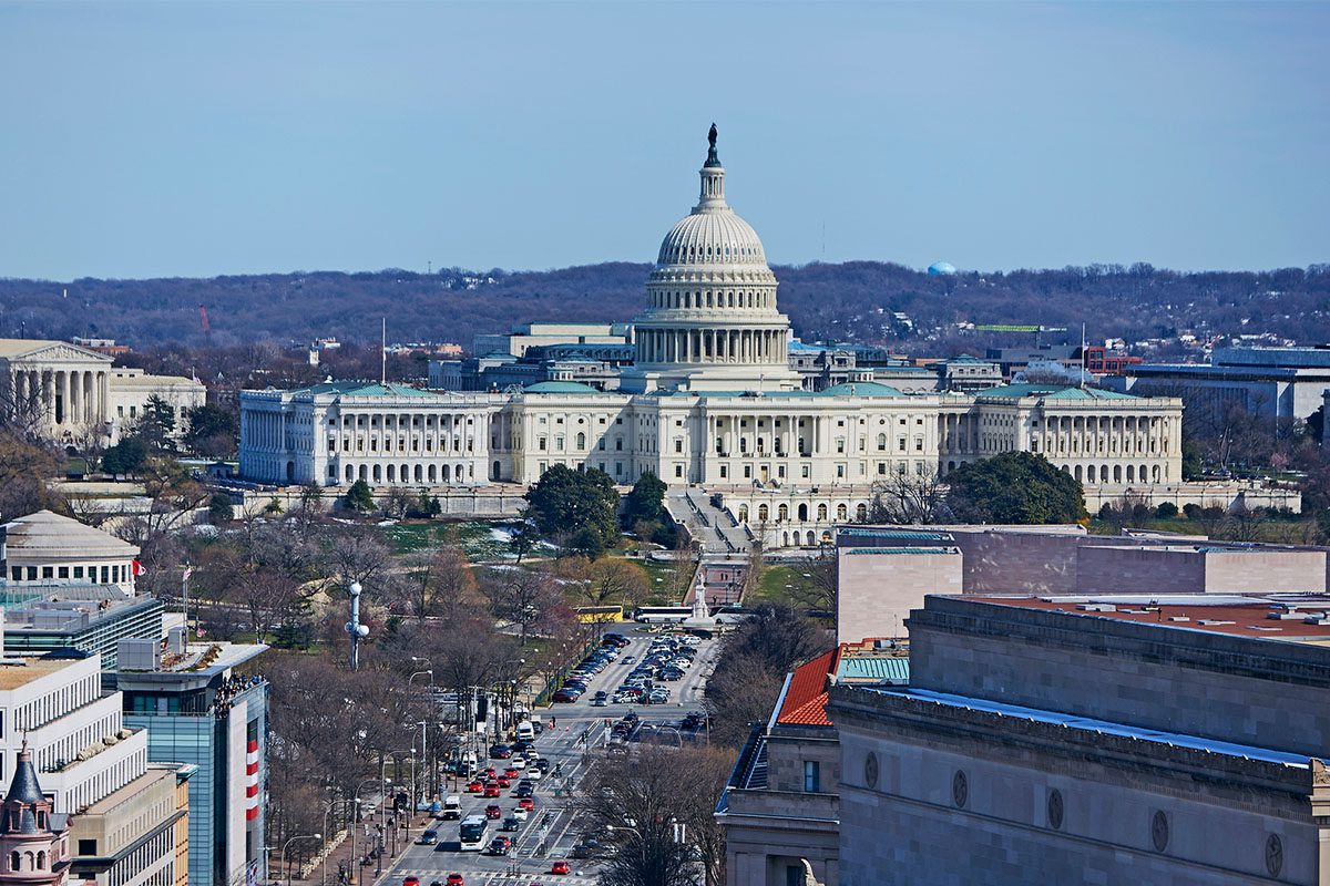 The United States Capitol building in Washington, D.C., viewed from a distance with surrounding streets and buildings visible in the foreground.