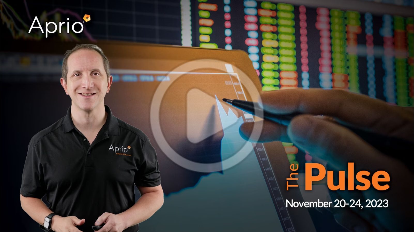 A man in an Aprio shirt stands in front of financial graphs on a screen, with text reading The Pulse November 20-24, 2023 displayed on the right.