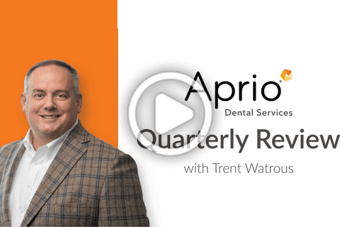 A man in a plaid suit stands next to the text “Aprio Dental Services Quarterly Review with Trent Watrous” on a white and orange background.
