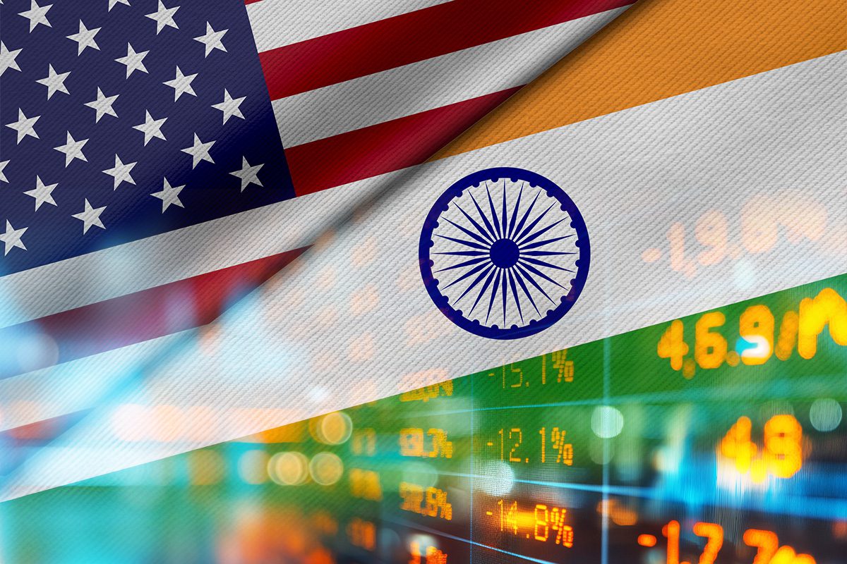 The United States and Indian flags are shown diagonally with stock market data and financial numbers in the background.