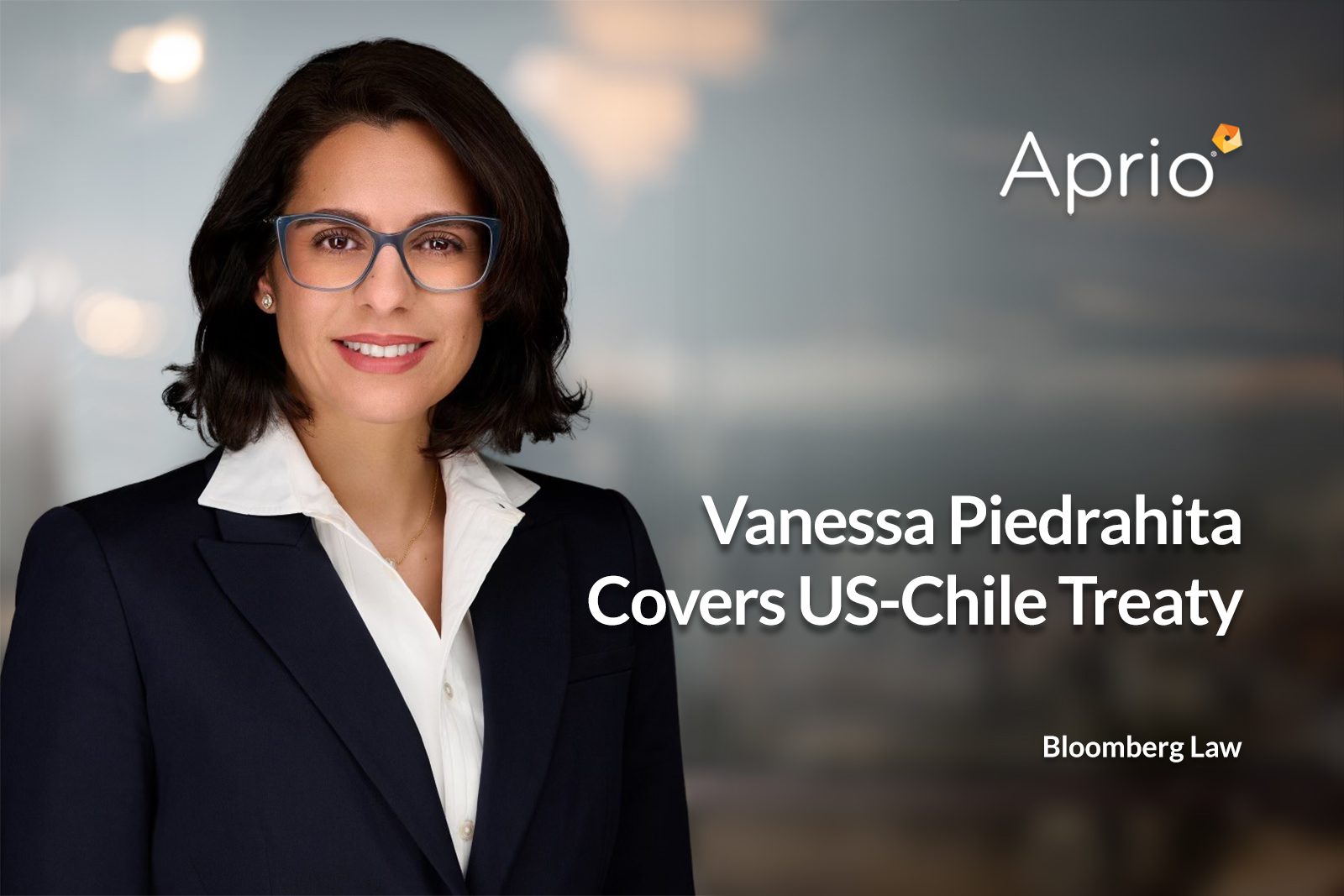 A woman in a dark blazer and glasses stands in front of a blurred background. Text reads: Vanessa Piedrahita Covers US-Chile Treaty with Aprio and Bloomberg Law logos.