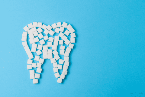 Sugar cubes arranged in the shape of a tooth on a blue background.