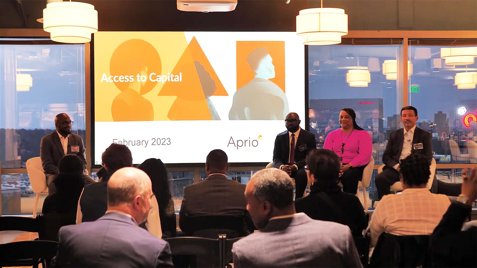 A panel of four speakers sits on stage in front of an audience during an Access to Capital event by Aprio held in February 2023.