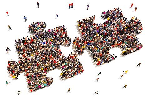 Large group of people standing together in the shape of two interlocking puzzle pieces on a white background.