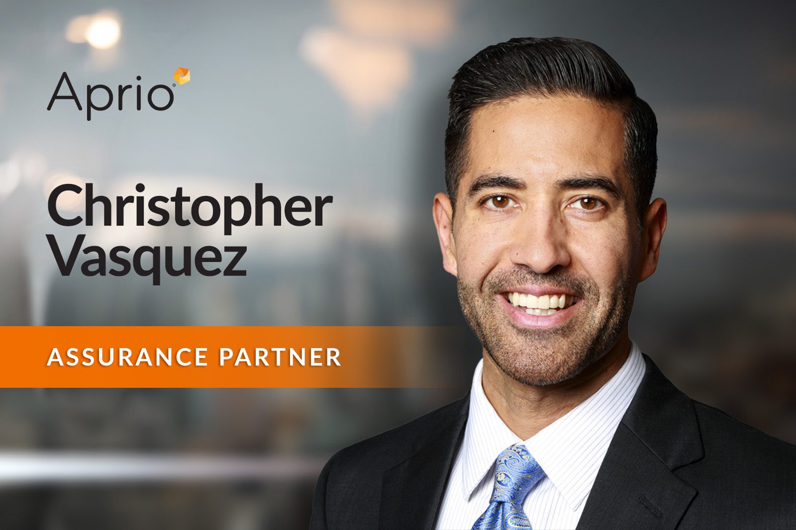 Professional headshot of a man in a suit with text: Aprio, Christopher Vasquez, Assurance Partner on a blurred office background.