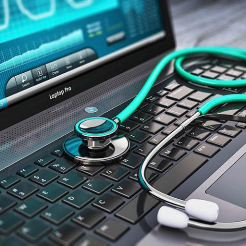 A stethoscope rests on the keyboard of a laptop with a medical chart displayed on the screen in the background.
