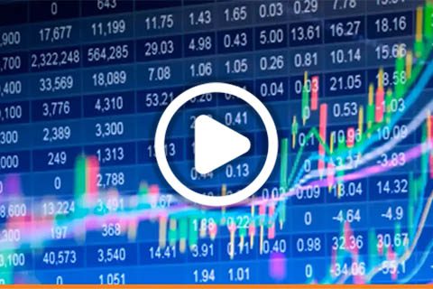 A digital screen displays stock prices and fluctuating line graphs; a play button overlay suggests this is a video about financial markets.