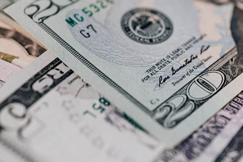 Close-up view of overlapping U.S. dollar bills, including a twenty-dollar bill and parts of other denominations.