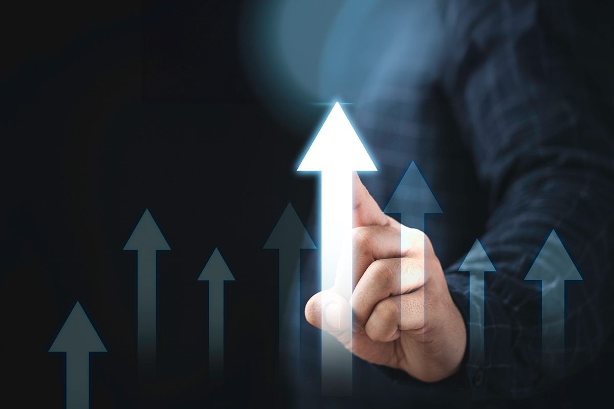 A person in a dark shirt touches a glowing upward arrow among several translucent arrows, symbolizing growth or progress.