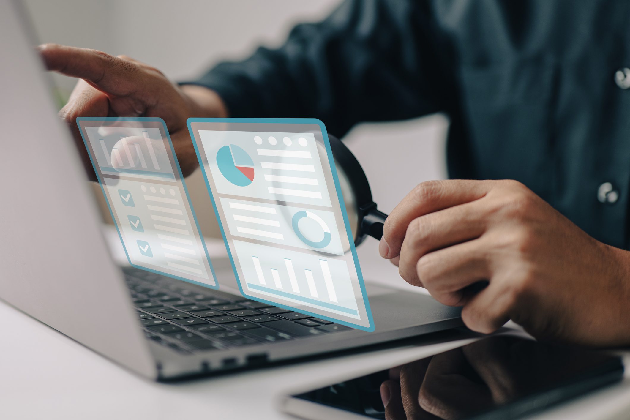 Person using a laptop with virtual data dashboards displaying charts and graphs, suggesting data analysis or business analytics.