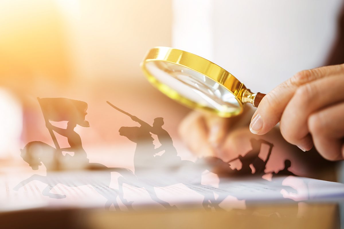 A hand holding a magnifying glass over paperwork, with shadowy silhouettes of people holding flags and swords appearing on the surface.