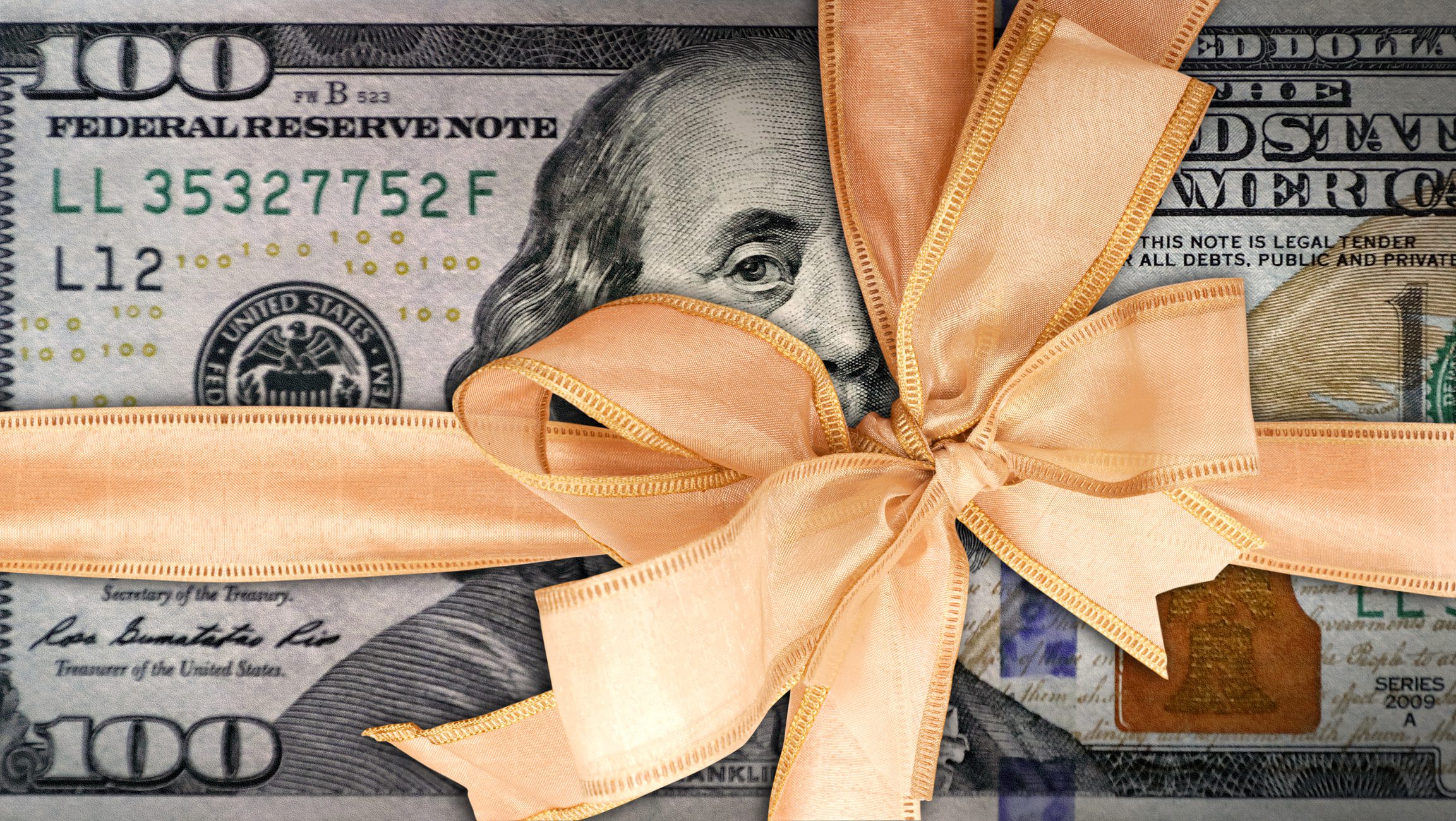 A US $100 bill wrapped with a large gold ribbon and bow, symbolizing money as a gift.