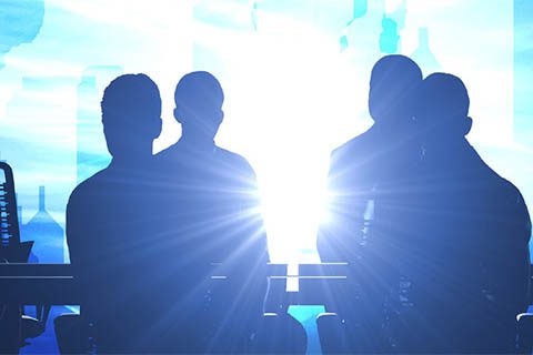 Four people in silhouette are seated facing a bright light source, creating a strong glow and obscuring their features.