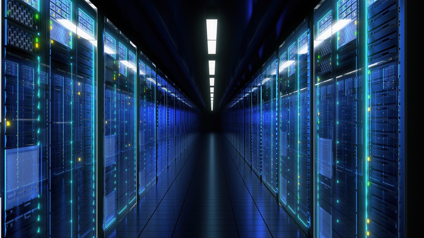 A corridor lined with illuminated server racks in a modern data center, with blue LED lights reflecting off the glass doors.