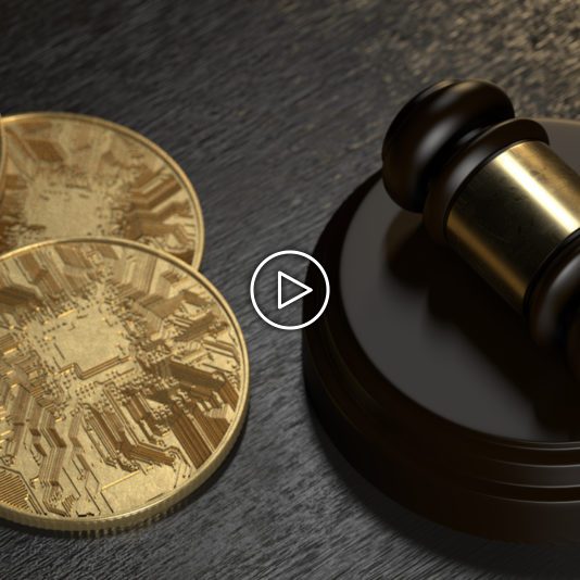 Two gold coins with circuit designs lie next to a wooden judges gavel on a dark surface.