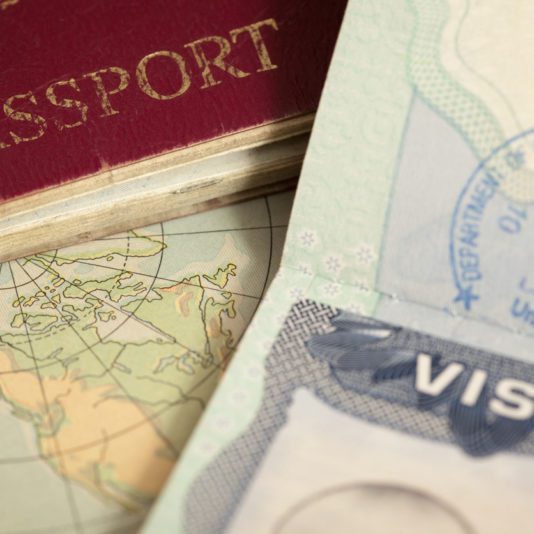 Close-up of a passport, a map, and a visa page with a visible visa stamp.