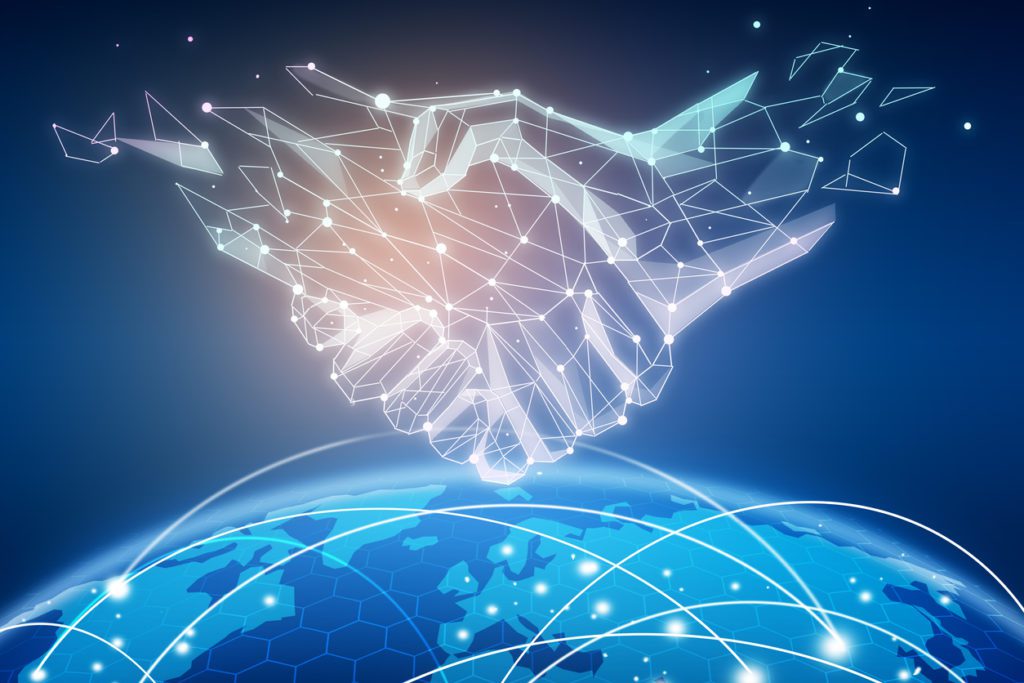Digital rendering of two polygonal hands shaking above a glowing globe, symbolizing global partnership and technology connections.