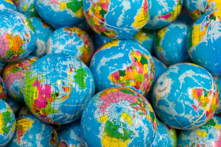 A pile of small inflatable globes showing colorful world maps with various continents and countries.