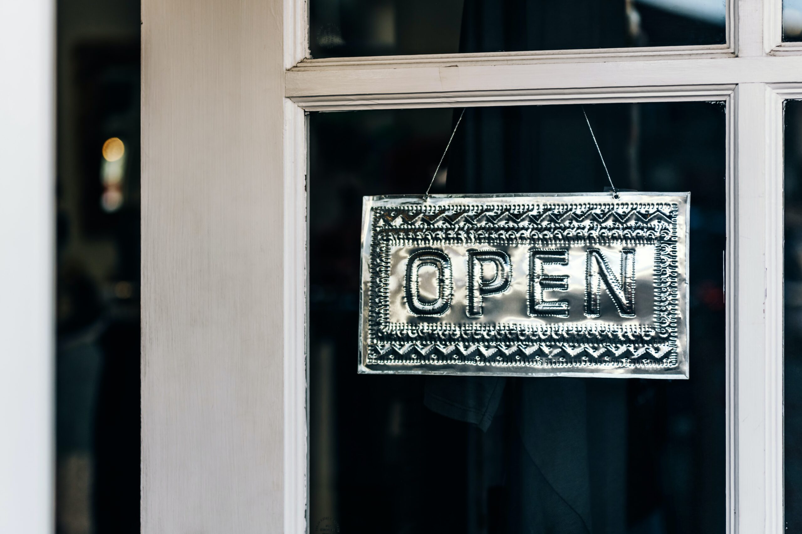 A metal OPEN sign hangs on a glass door, indicating that the business is currently open.