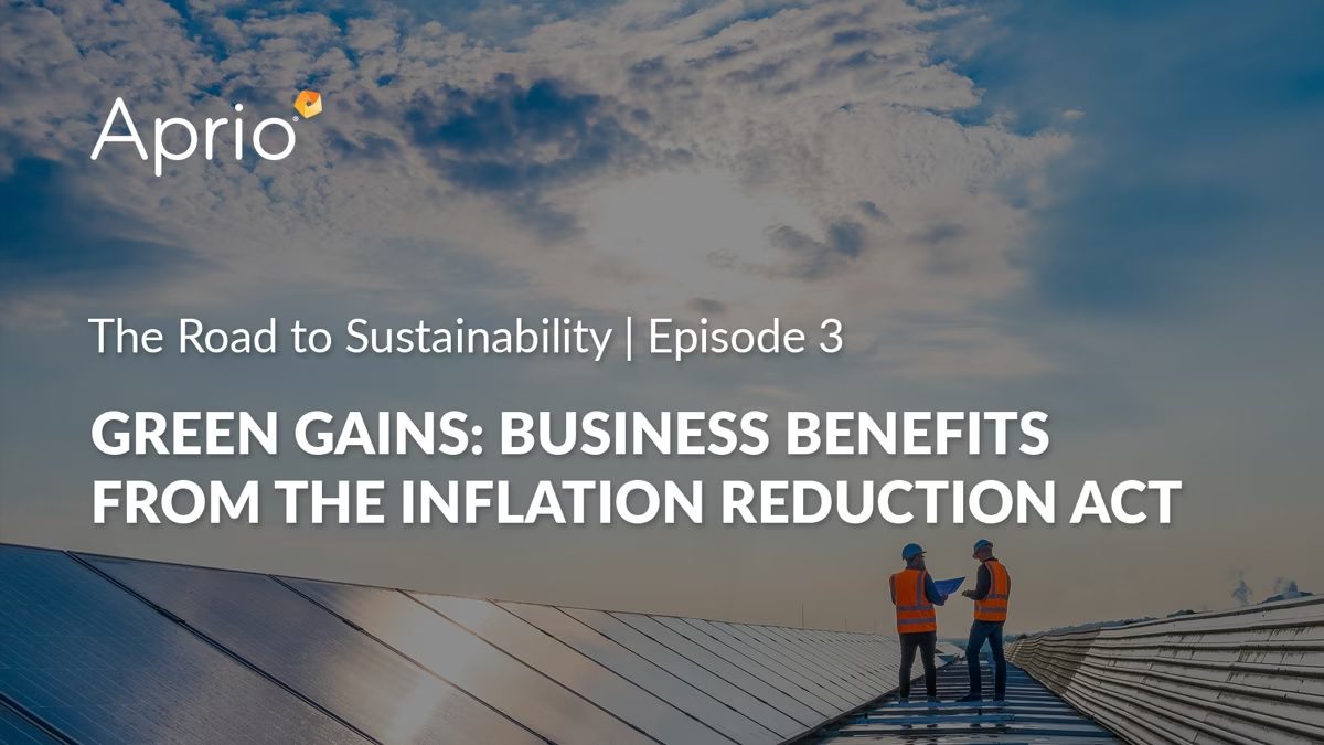 Two people in safety gear stand on a rooftop with solar panels at sunset. Text discusses business benefits from the Inflation Reduction Act in a sustainability video series by Aprio.