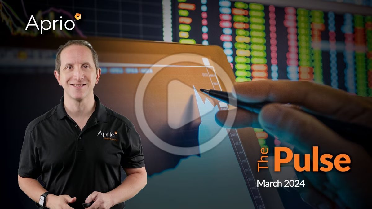 A man in an Aprio shirt stands in front of a tablet displaying a financial chart with colorful stock data in the background. Text reads: The Pulse March 2024.