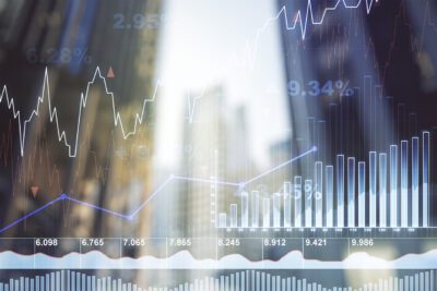Abstract image of financial graphs and stock market data overlaid on a blurred cityscape, showing fluctuating line and bar charts.
