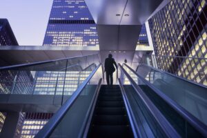 Businessman on top of moving escalator at modern illuminated business district