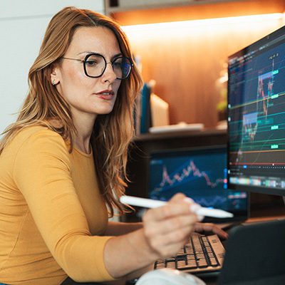 A young woman is sitting in her home and attentively observing the stock market using cryptocurrency graphics