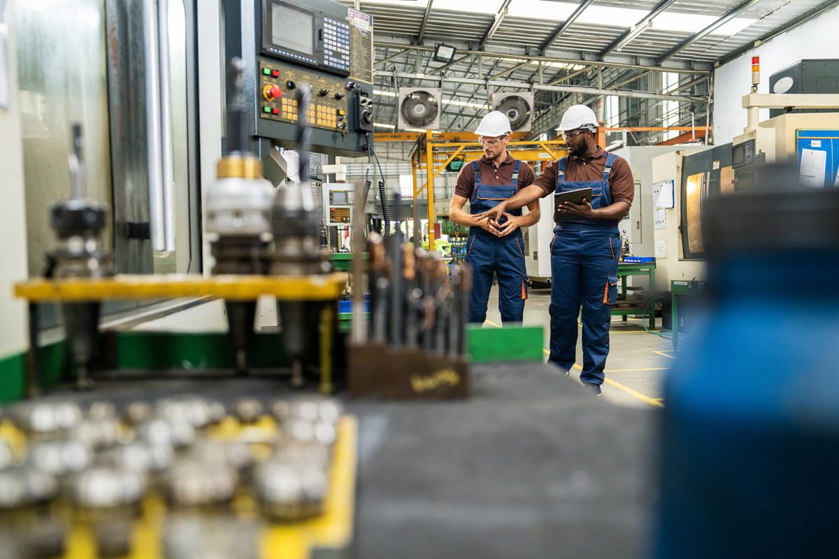 Engineer And Apprentice Using Automated Milling Machine
