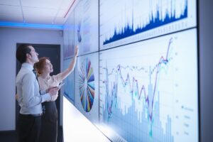 Business colleagues studying graphs on screen in meeting room